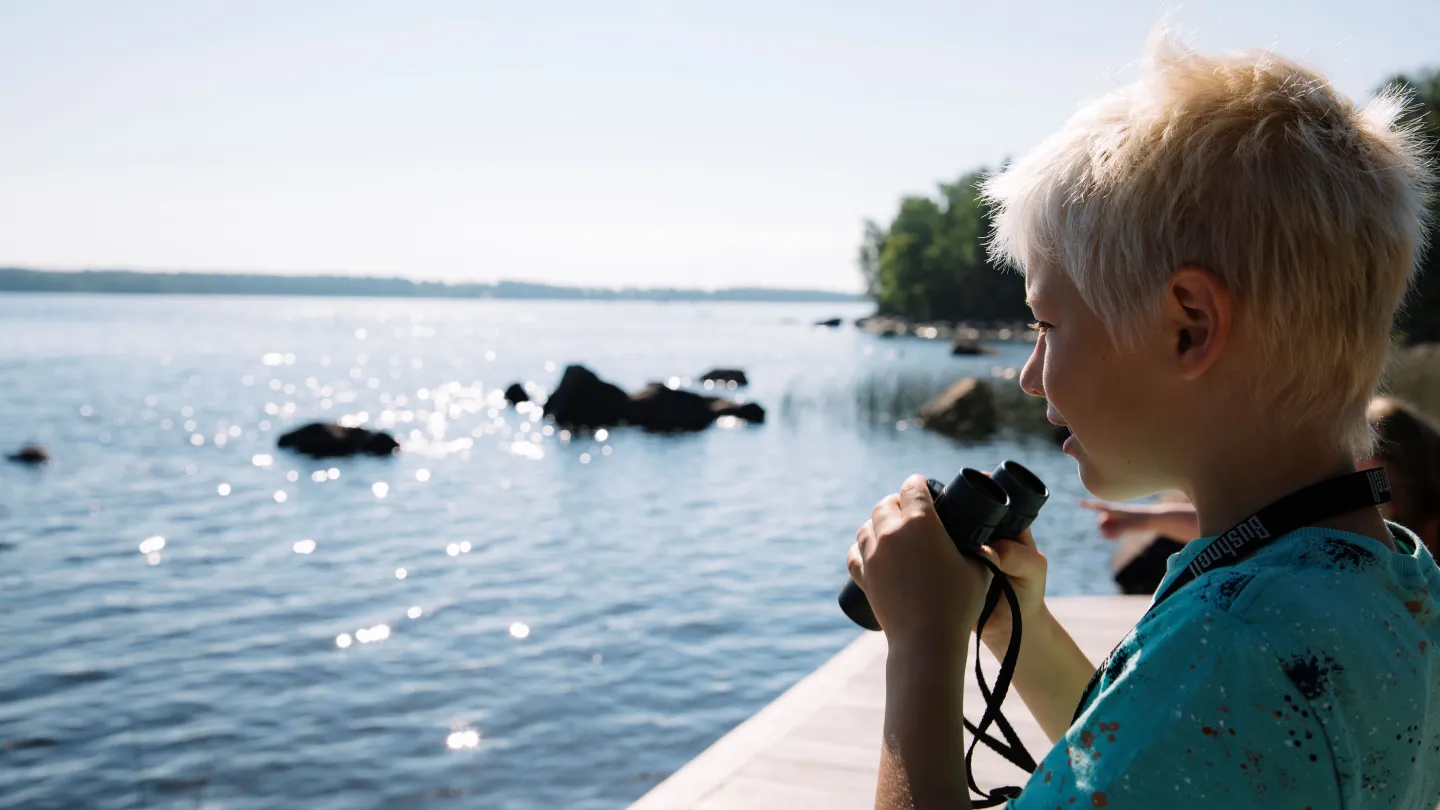 Barn med kikare vid sjö